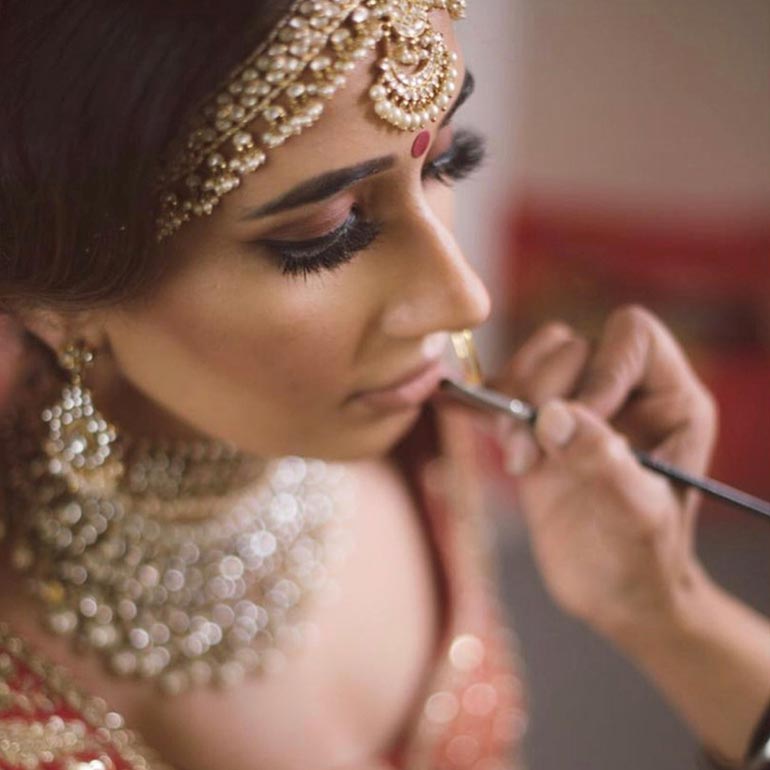 Indian bride putting on makeup for wedding ceremony