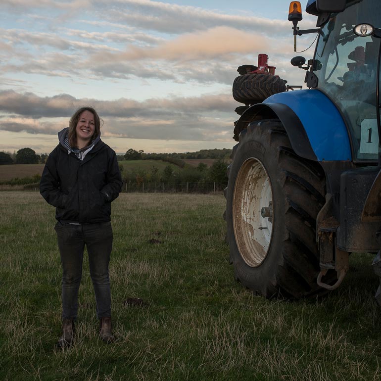 Female farmer next to blue tractor